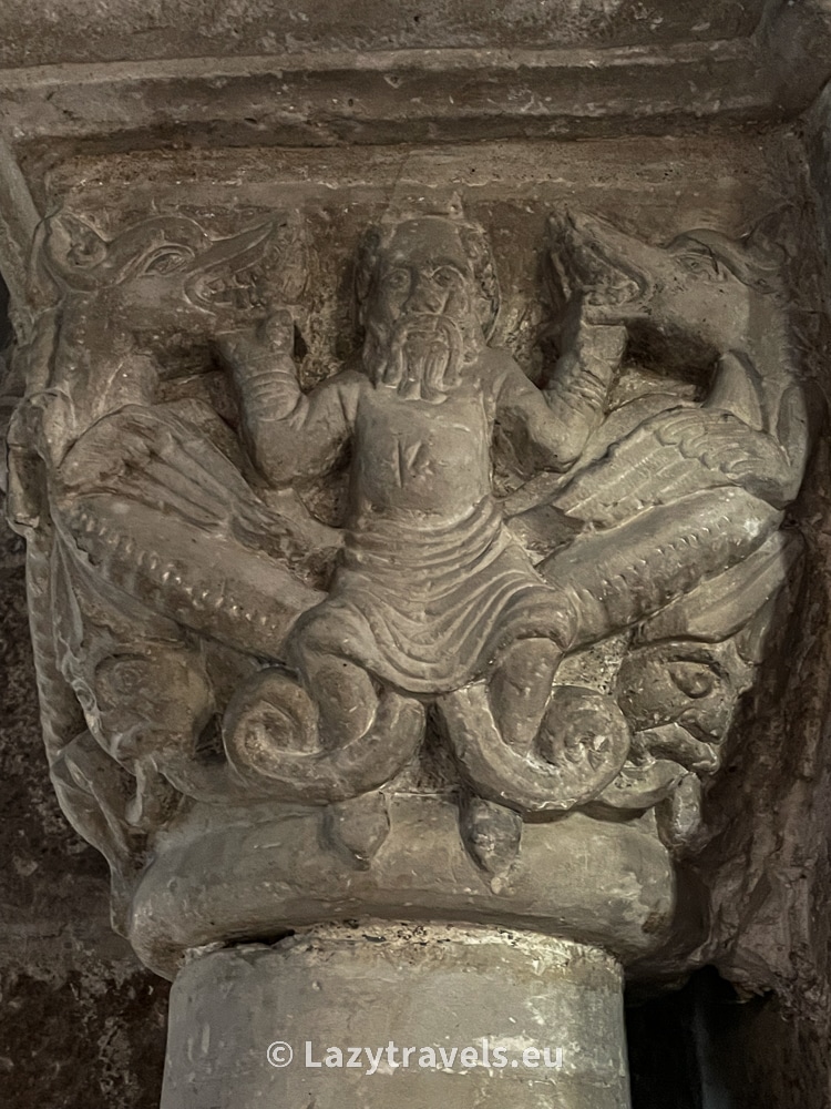 A capital with a man holding dragons out of his mouth