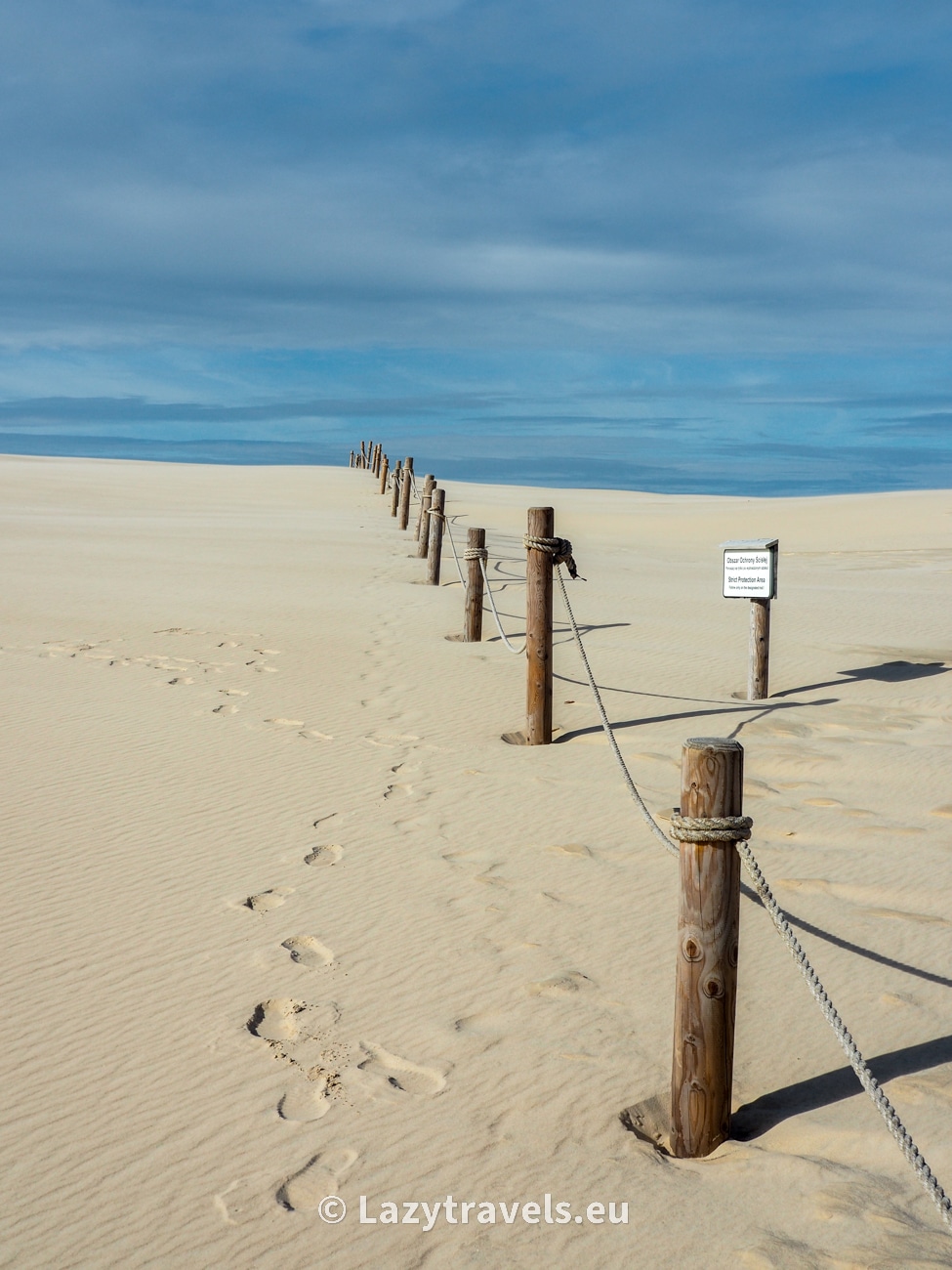 The sand of the dune slowly hides the signs