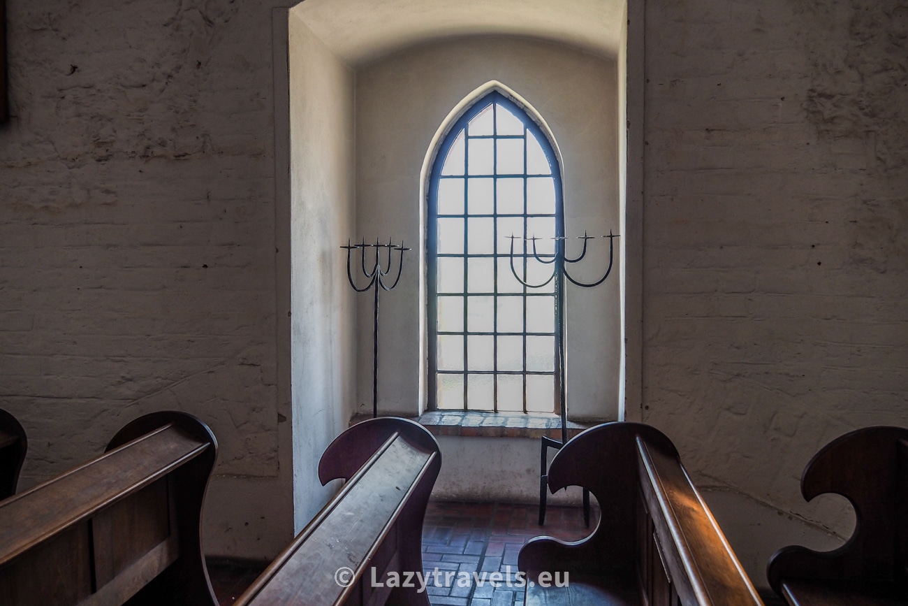 A window in the castle chapel in Gniew. Arches can be seen next to the pews; these are traces of a past renovation of the castle